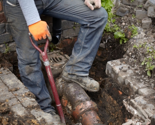 An image of a sewer contractor working on a pipe.