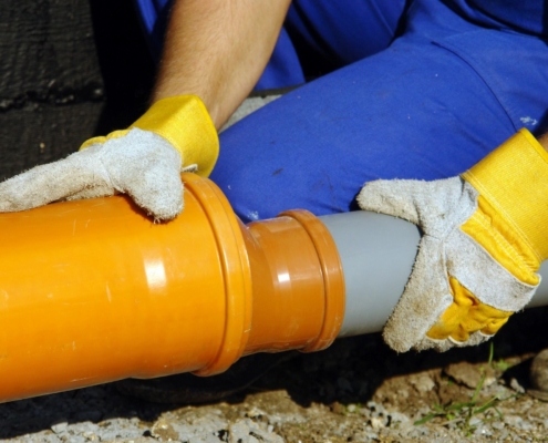 A plumbing contractor working on a sewer pipe.
