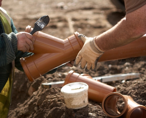 Two plumbing contractors working together on a pipe repair.